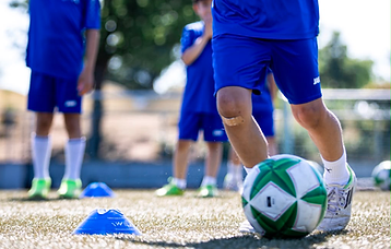 Junger Spieler im blauen PK-Trikot beim Dribbling