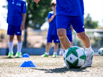 Junger Spieler im blauen PK-Trikot beim Dribbling