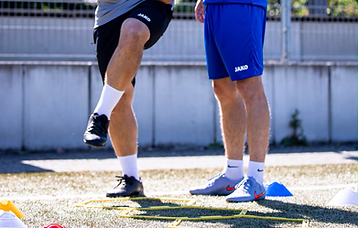 Trainer balanciert den Ball – Spieler beobachtet aufmerksam