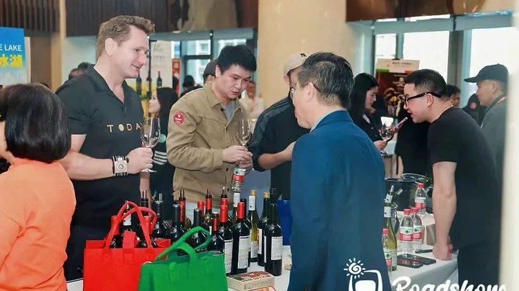 Regional wine distributor executive inspecting bottled wine inventory in a modern temperature-controlled wholesale warehouse.