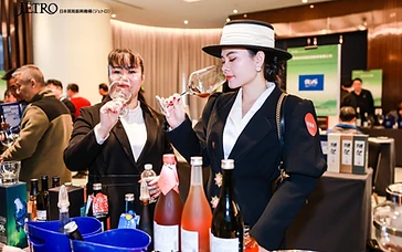 Asian wine importers and buyers reviewing organic wine certification documents and sample bottles at a professional trade tasting.