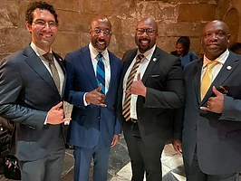 Brothers posing with US Senator Raphael Warnock
