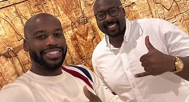 Brothers posing before an ancient carved artifact in a museum