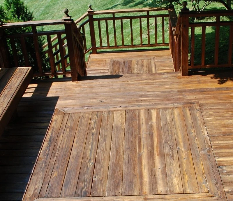 Wooden backyard deck with railings and built-in bench overlooking a green lawn