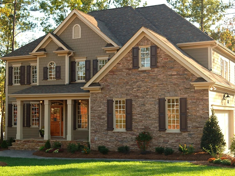 Two-story home with stone and siding exterior surrounded by trees