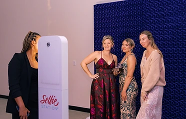 Three women posing with an award at a blue textured backdrop