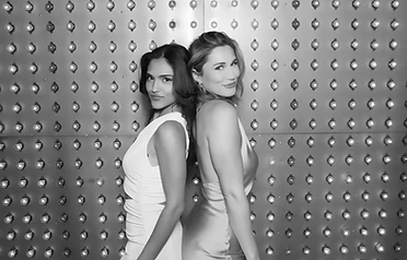 Two women posing back to back in black and white