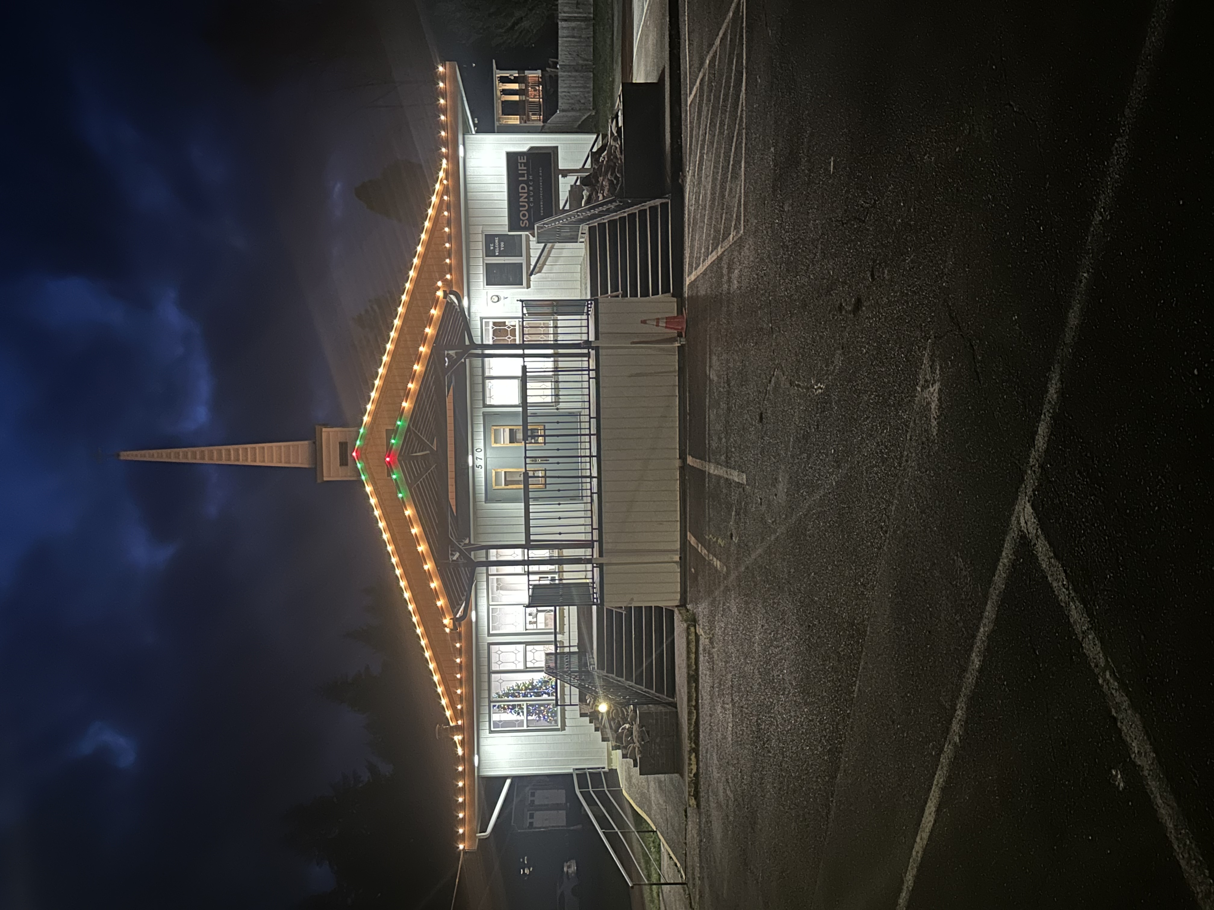 Building with amber and green C9 roofline lighting at night