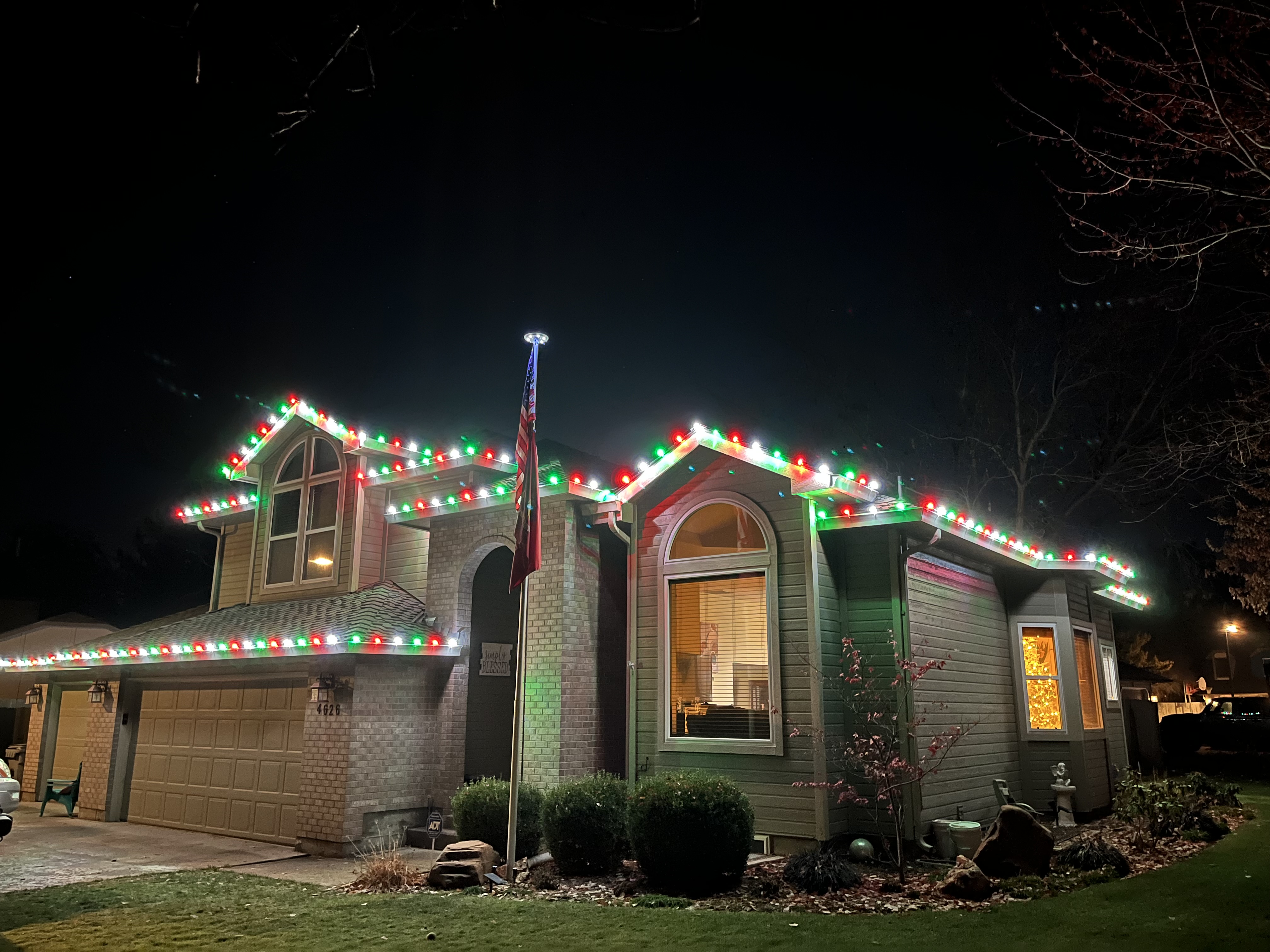 Two-story home with alternating red and green C9 roofline lighting