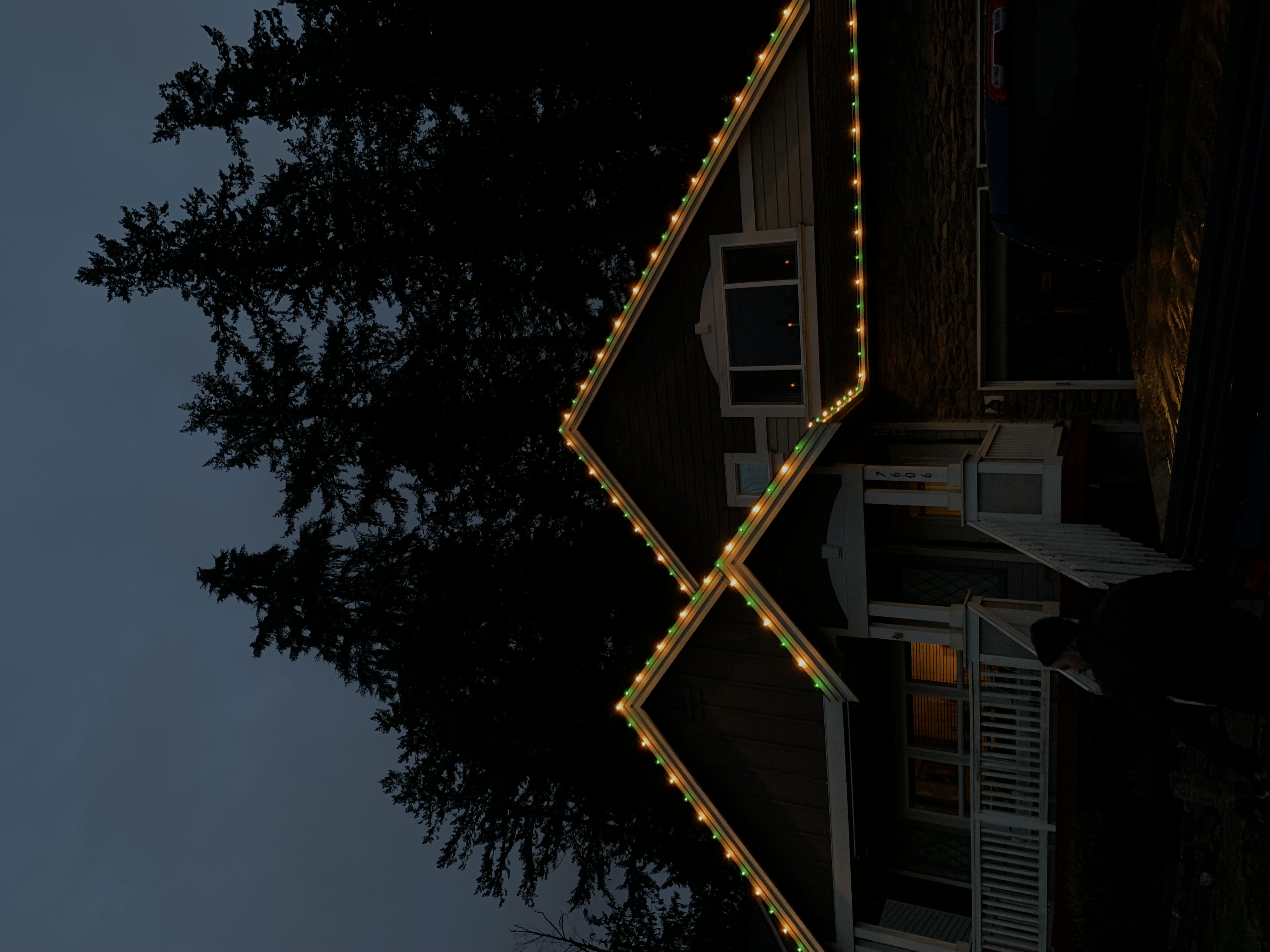 Two-story home with warm white and green C9 roofline lighting on gables