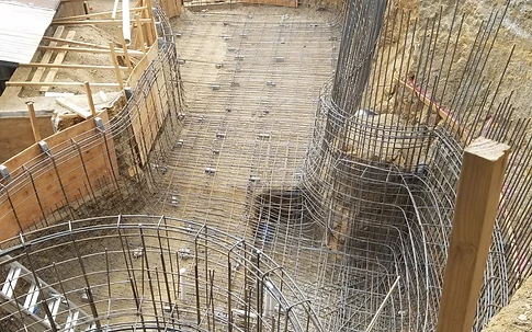 Pool shell rebar grid with a circular spa cage in the foreground and formwork around the perimeter