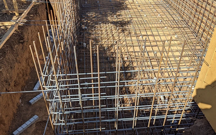 High-angle view of a pool foundation reinforcing steel grid and wooden formwork