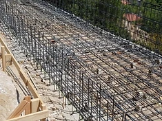 High-angle view of a complex pool rebar grid on a hillside site