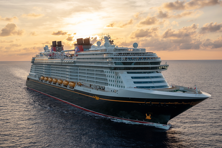 The Disney Wish cruise ship sailing through open water at golden-hour sunset