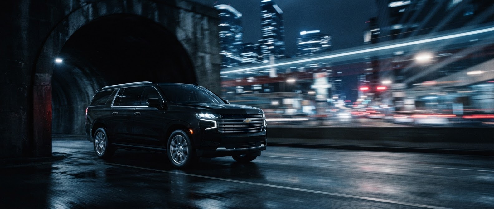 Black Suburban Premier emerging from a tunnel into city lights