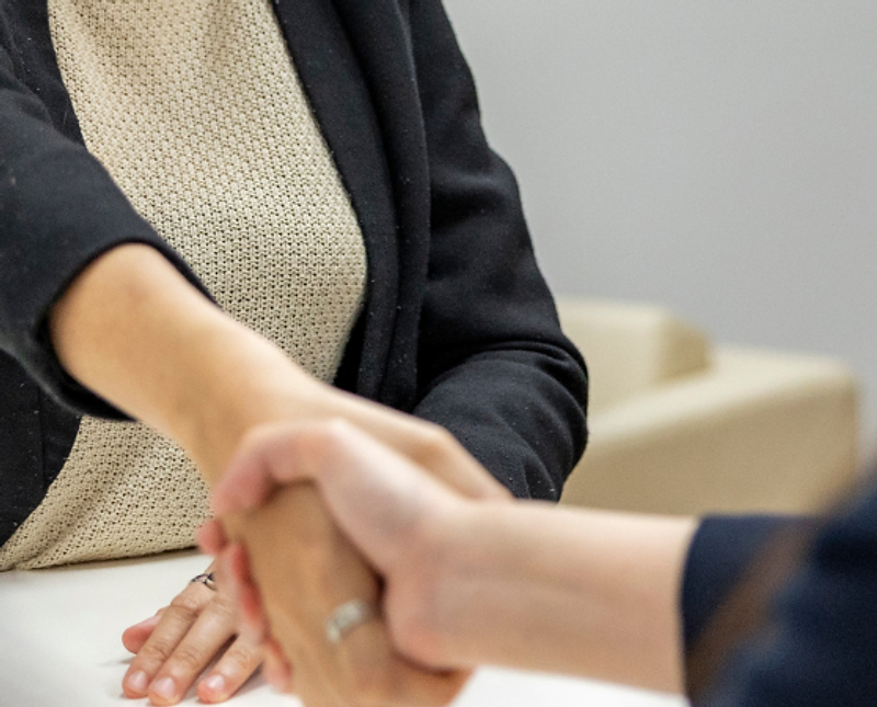 Employer greeting a candidate across a desk