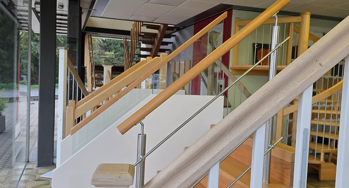 Holztreppe mit weißen Balustern und Edelstahlstäben im Ausstellungsraum