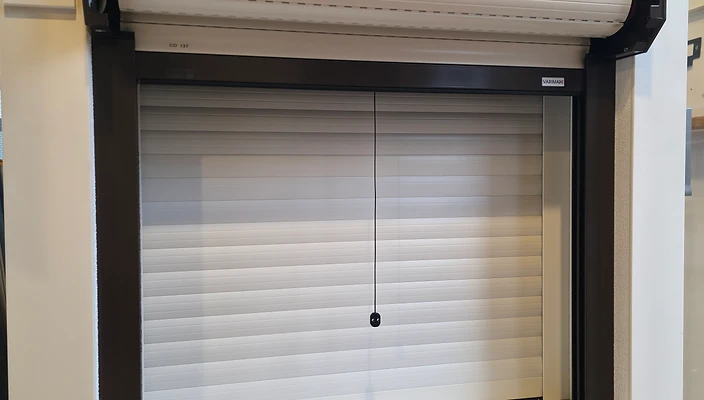 Rollladen mit teilweise heruntergelassenem Behang an einem Fenster