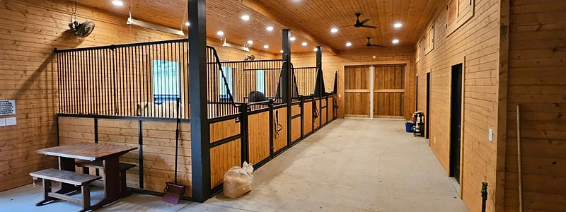Custom horse barn aisle with stalls built by Backyard and Barns