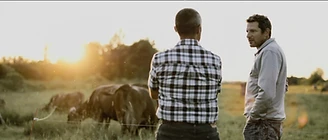 Two men talking at golden hour beside the herd