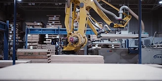 A robot arm sorting hardwood boards in the plant