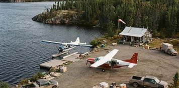 Floatplane and turbo-prop aircraft at a subarctic Athabasca Basin aviation base with supply trucks at Stony Rapids, Saskatchewan