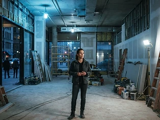 Business owner standing in a large empty commercial unit under renovation with blue work lights