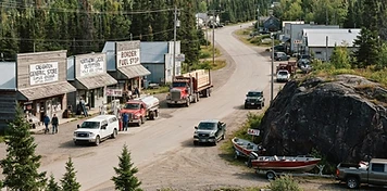 Border-service commercial street with transport trucks and fishing-lodge boats at Creighton beside Flin Flon, Saskatchewan