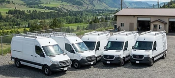 Service vans lined up at a Quispamsis contractor compound at midday.