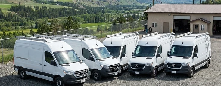 Service vans lined up at a Quispamsis contractor compound at midday.