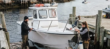Crew preparing a small commercial tour vessel at a coastal service dock in St. Andrews.