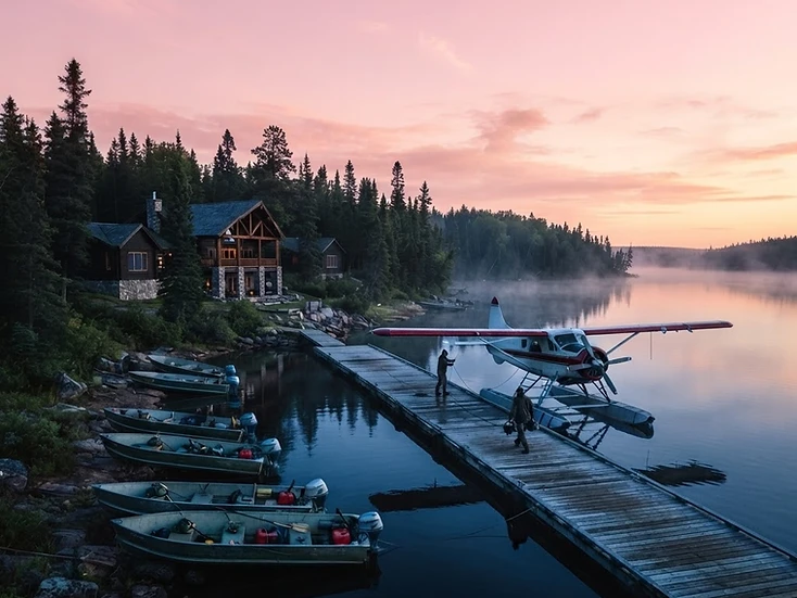 Floatplane at a northern lake lodge dock on a boreal shoreline at first light
