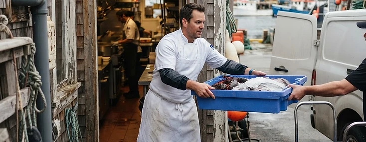Chef receiving crates of fresh seafood at the back door of a Shediac coastal restaurant.