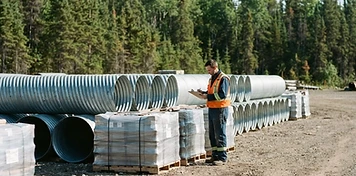 Rail worker inspecting freight cars beside a service truck at a bright northern Manitoba rail siding