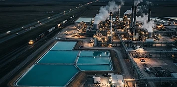 Turquoise solution-mining evaporation ponds beside a nitrogen fertilizer plant on the Saskatchewan prairie at dusk