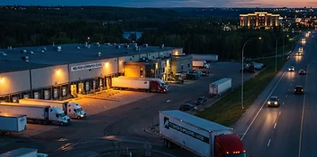 Distribution warehouses with a highway tractor pulling out onto the QEII corridor in Red Deer at dusk