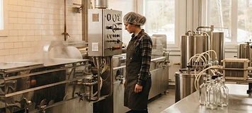 Operator monitoring stainless maple-processing and bottling equipment in a Saint-Quentin production room.