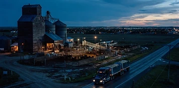 Grain elevators and cattle facilities at the edge of a southwestern Saskatchewan city at dusk