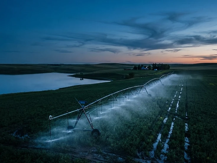 Centre-pivot irrigation system watering farmland near Lake Diefenbaker at dusk