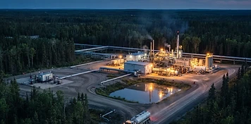 Thermal in-situ oil sands plant with well pads and pipeline corridors through boreal forest near Cold Lake at dusk