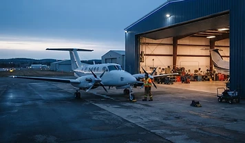 Business aircraft and aviation service professional at a regional airport hangar at dawn