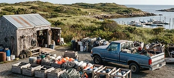 Service pickup and marine-supply crates organized in an island equipment yard in Lamèque.