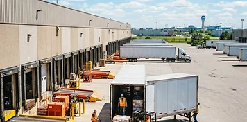 Warehouse crews unloading freight at sunlit loading docks in Mississauga, Ontario