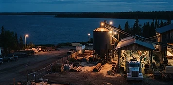 Sawmill and pellet-plant yard with delivery truck at a lake shoreline in Slave Lake at dusk