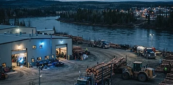 Log trucks and forestry-service buildings in a northern Saskatchewan river city