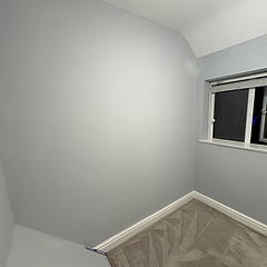 Bedroom corner in soft blue-grey with new carpet and white skirting