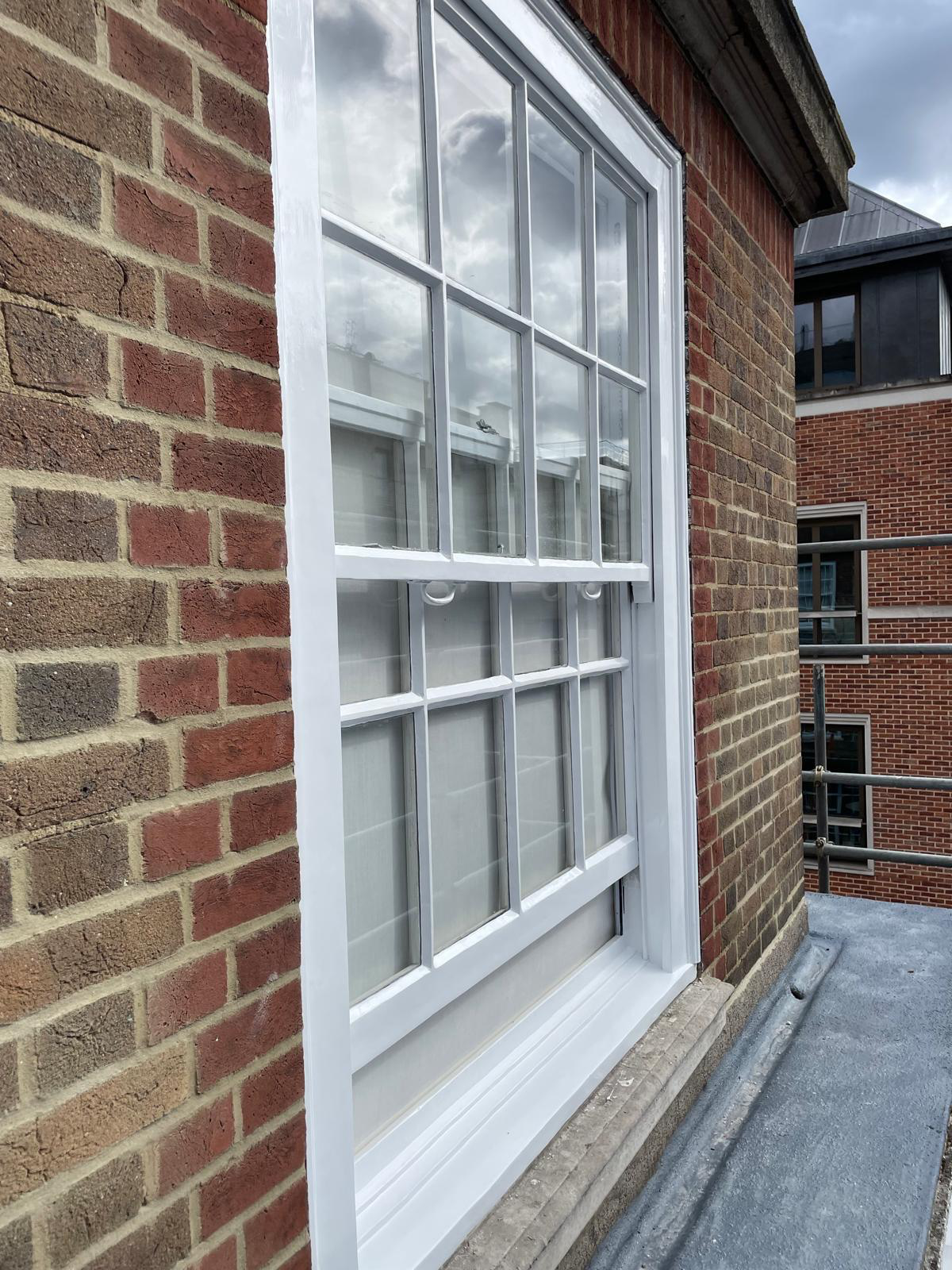 Restored white sash window set into a red brick facade