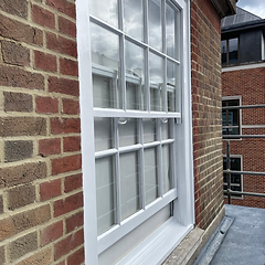 Restored white sash window set into a red brick facade