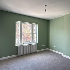 Finished bedroom with sage green walls and traditional sash window