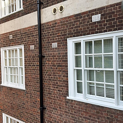 Brick facade refreshed with bright white sash windows and masonry paint